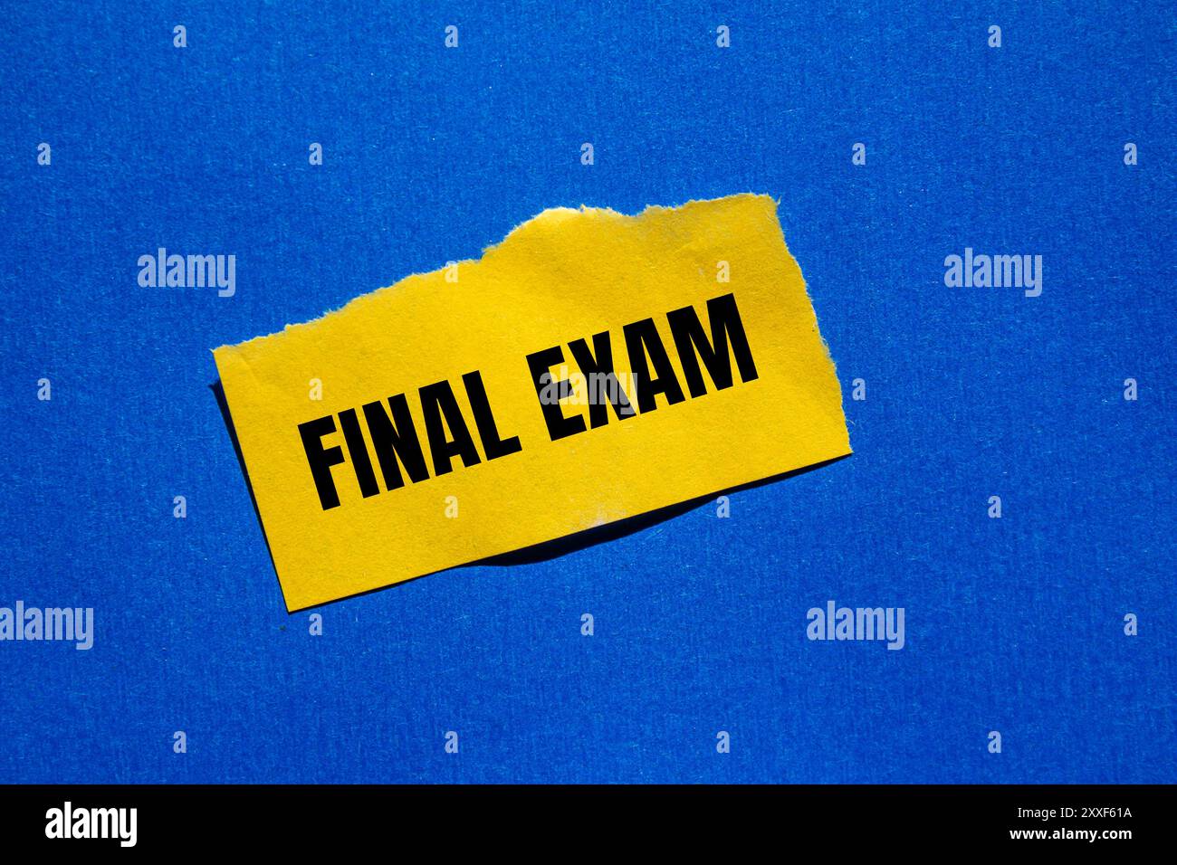 Messaggio finale dell'esame scritto su un foglio di carta giallo strappato con sfondo blu. Simbolo dell'esame finale concettuale. Copia spazio. Foto Stock