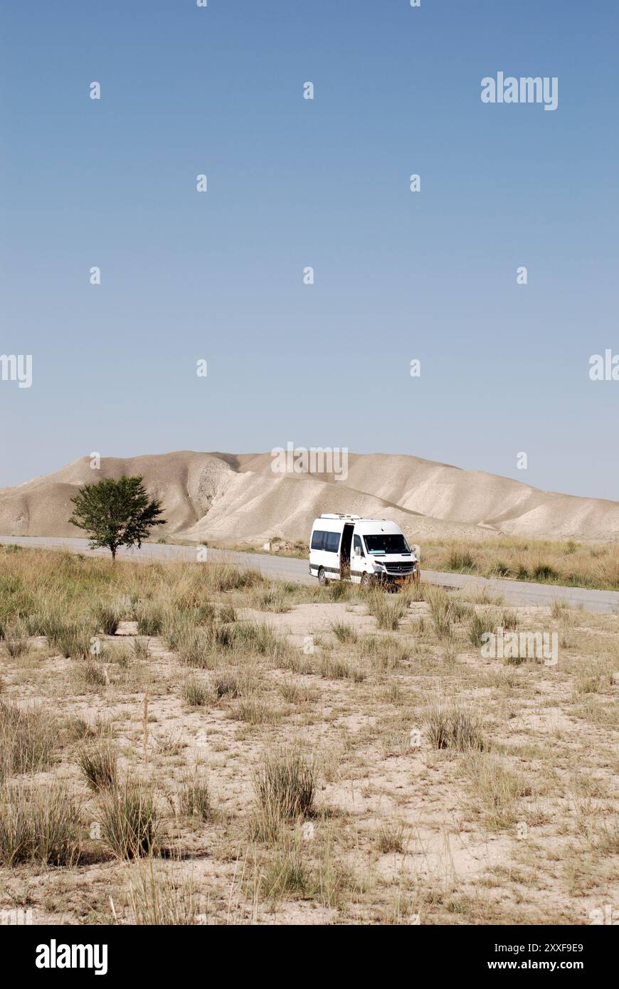 Un minibus parcheggiato sul ciglio della strada nel paesaggio montano del Kirghizistan Foto Stock