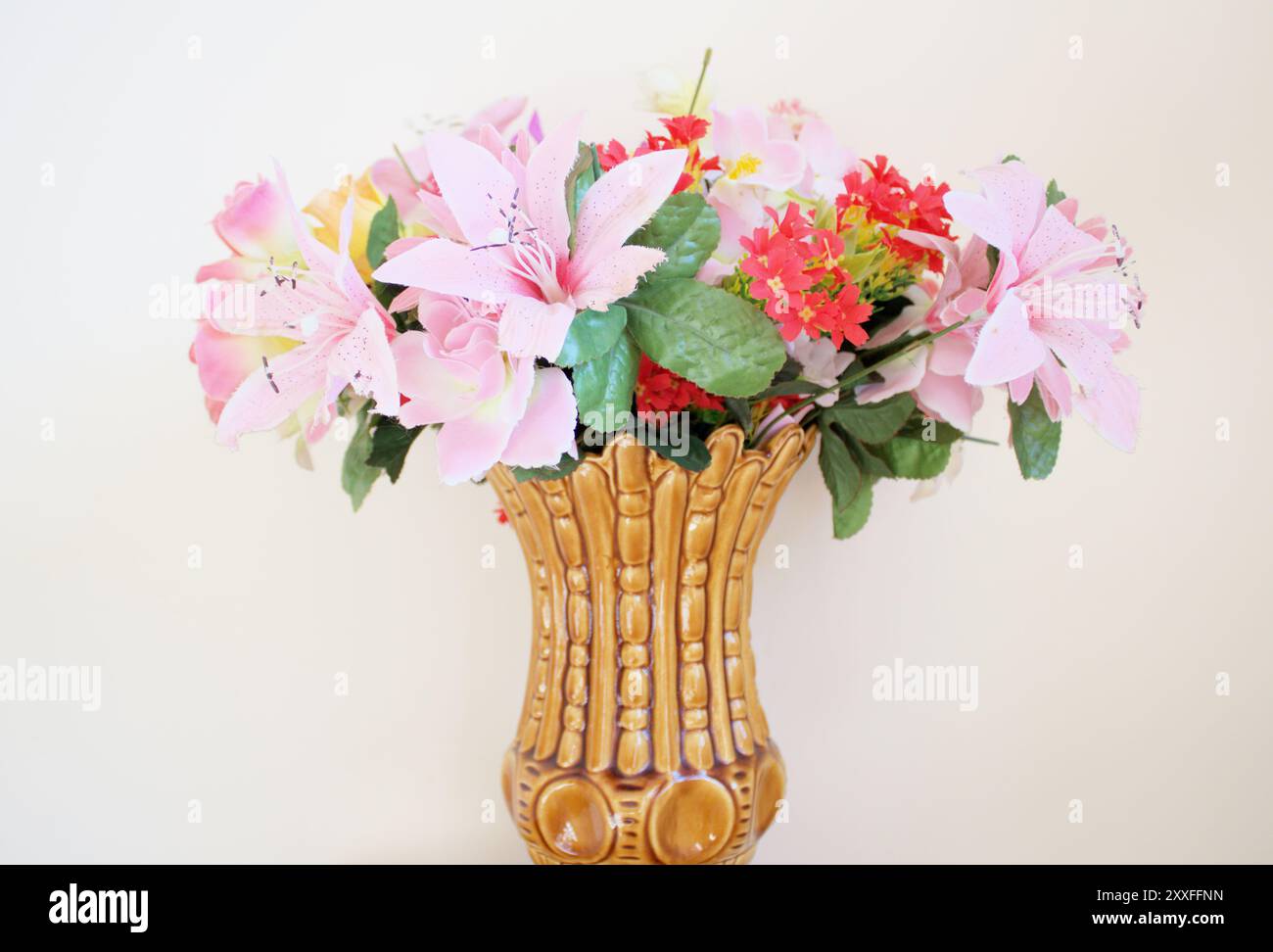 Studio orizzontale STILL Life girato di un vaso con fiori scenografici in plastica rosa e rossa al centro. Foto Stock