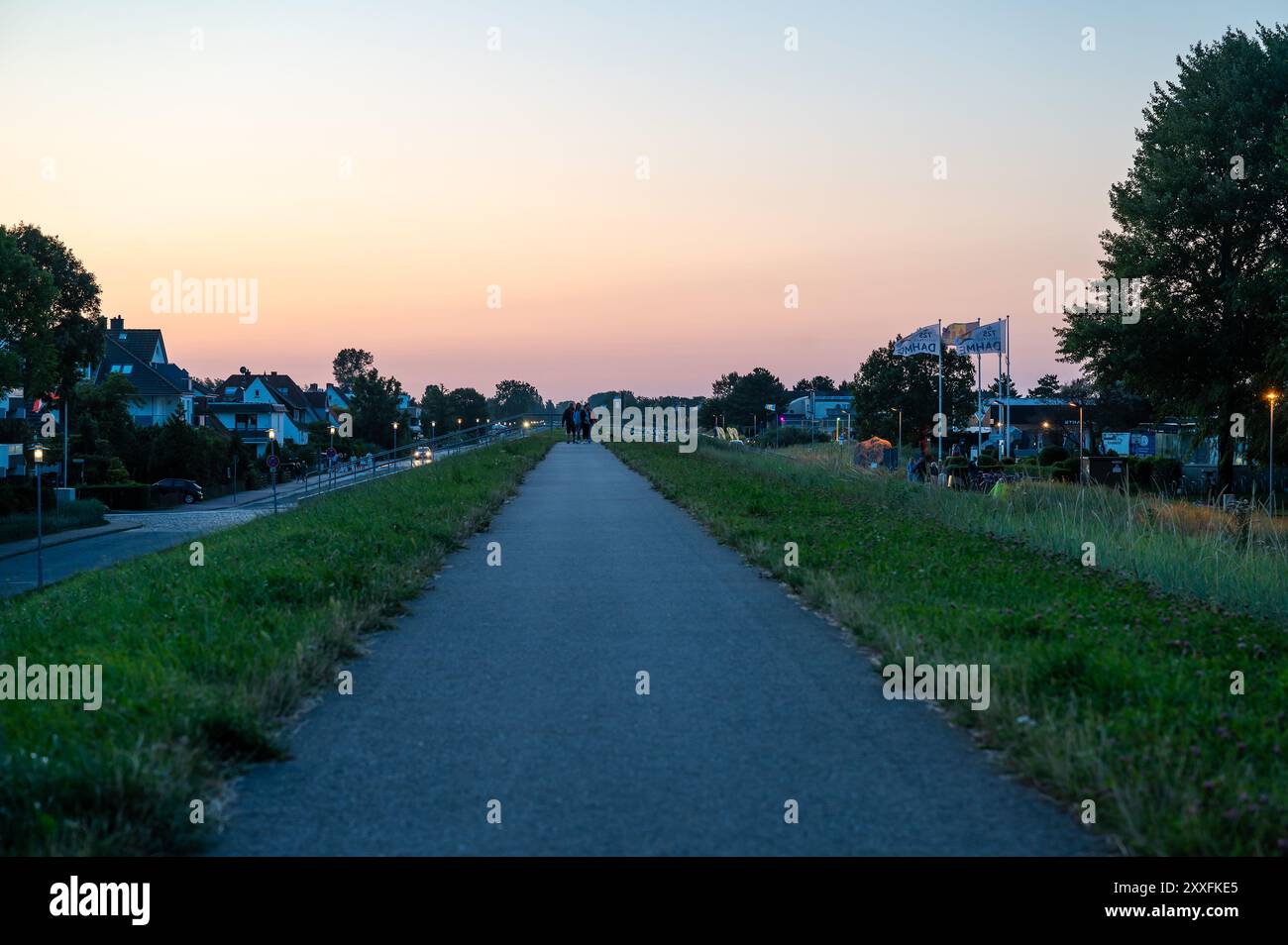 Dahme, Germania, 20 luglio 2024 - tramonto sulla diga con pista ciclabile sul mare. Foto Stock