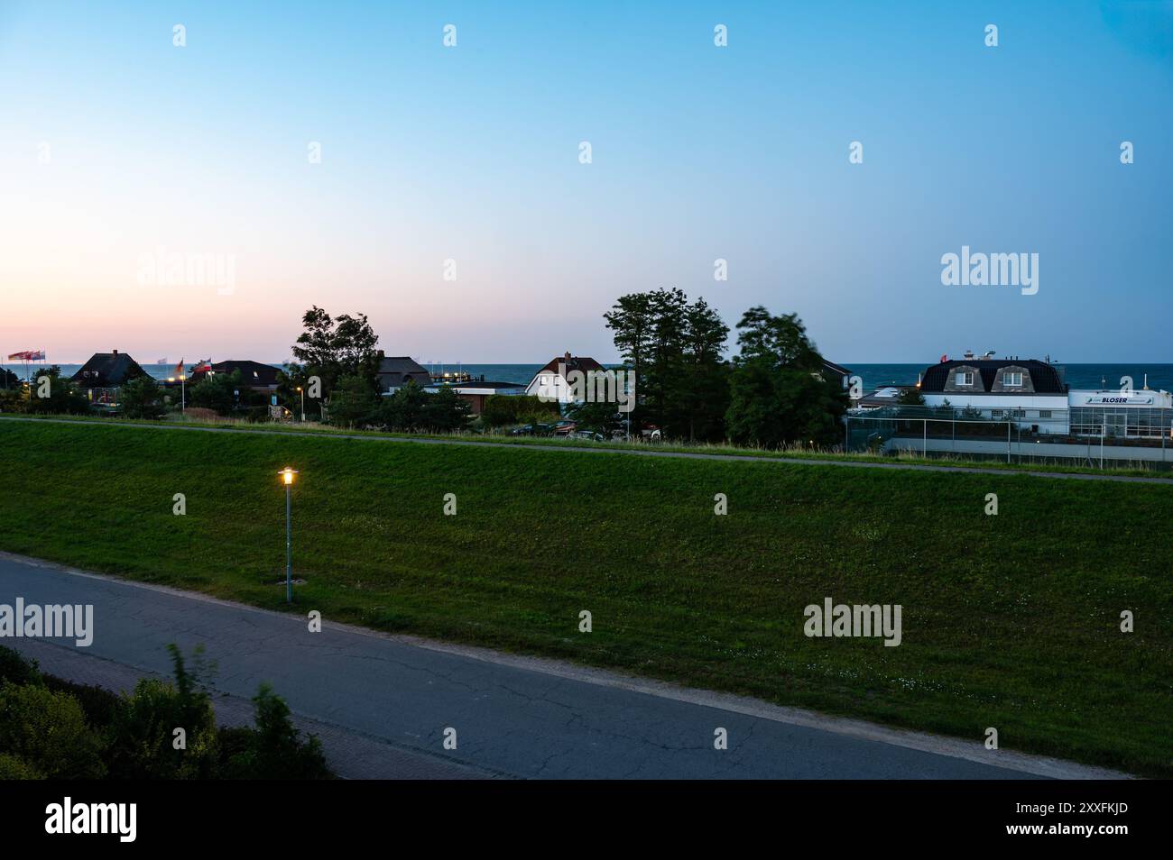 Dahme, Germania, 20 luglio 2024 - tramonto sulla diga con pista ciclabile sul mare. Foto Stock