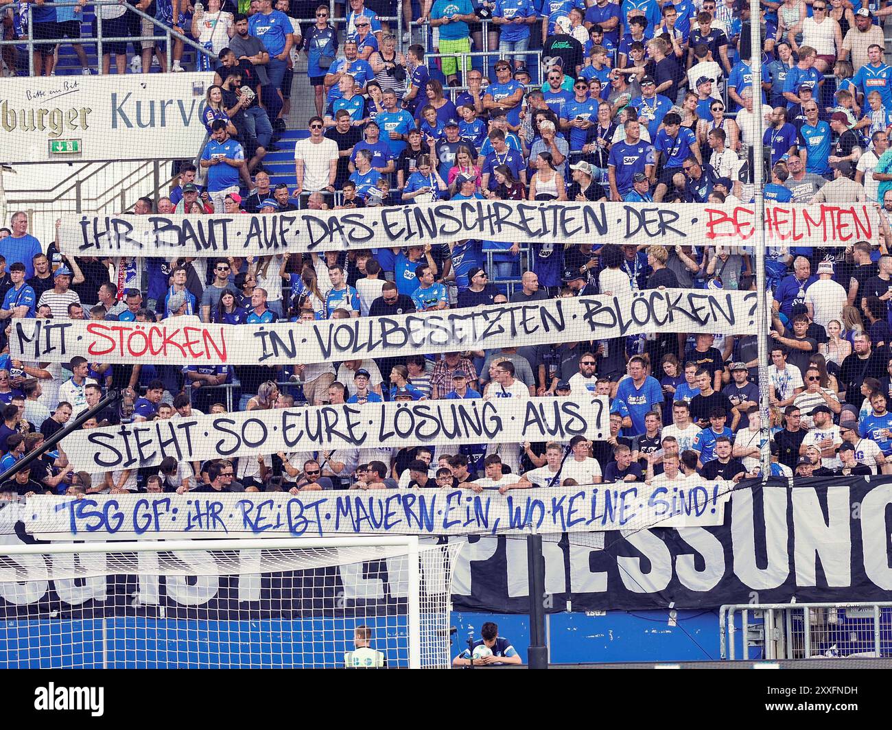 24 agosto 2024, Baden-Württemberg, Sinsheim: Calcio, Bundesliga 1, TSG 1899 Hoffenheim - Holstein Kiel, giorno 1 alla PreZero Arena. I fan di Hoffenheim presentano uno striscione di protesta con l'iscrizione 'si fa affidamento sull'intervento di uomini elmetti con bastoni in blocchi interi? Questa è la soluzione che fa per te? TSG GF: Stai abbattendo muri dove non CE ne sono!”. Foto: Heiko Becker/dpa - NOTA IMPORTANTE: In conformità con i regolamenti della DFL German Football League e della DFB German Football Association, è vietato utilizzare o far utilizzare fotografie scattate nello stadio e/o del Foto Stock