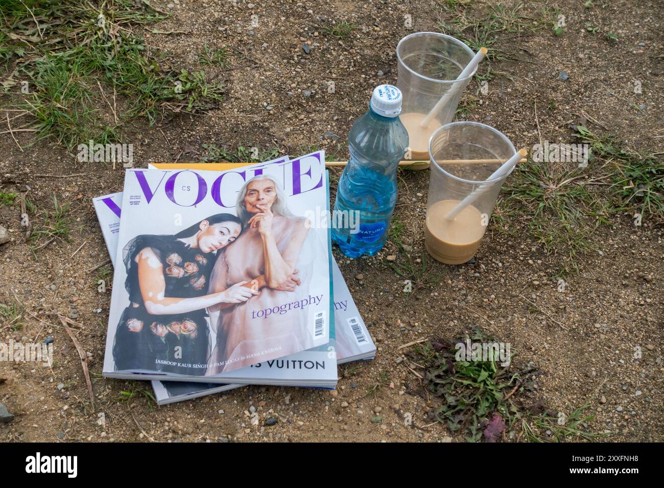 Rivista Vogue, lettura estiva, tazze di plastica vuote cannucce bottiglia di acqua sotterranea Foto Stock