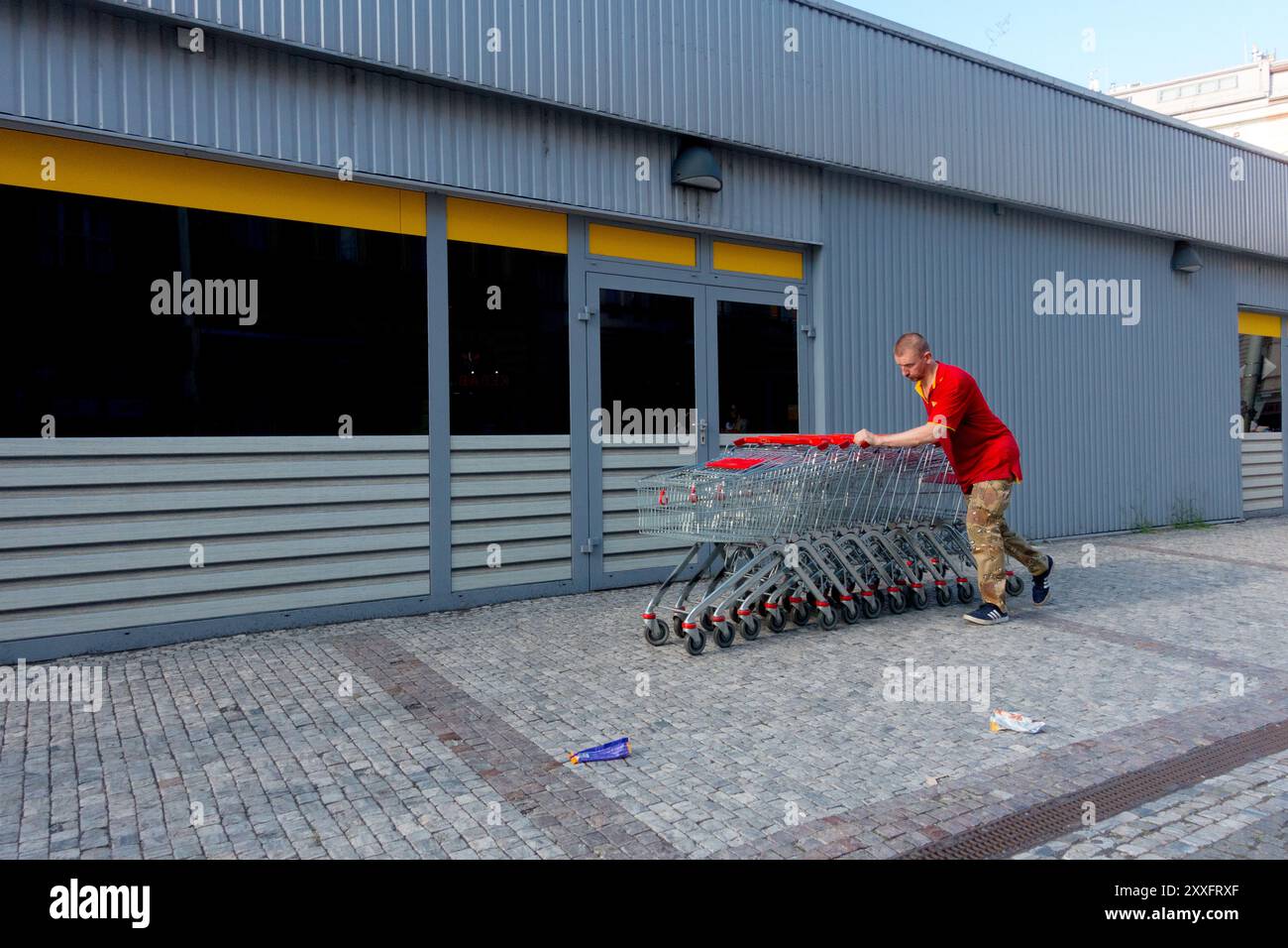 Lavoratore che spinge i carrelli dei supermercati Foto Stock