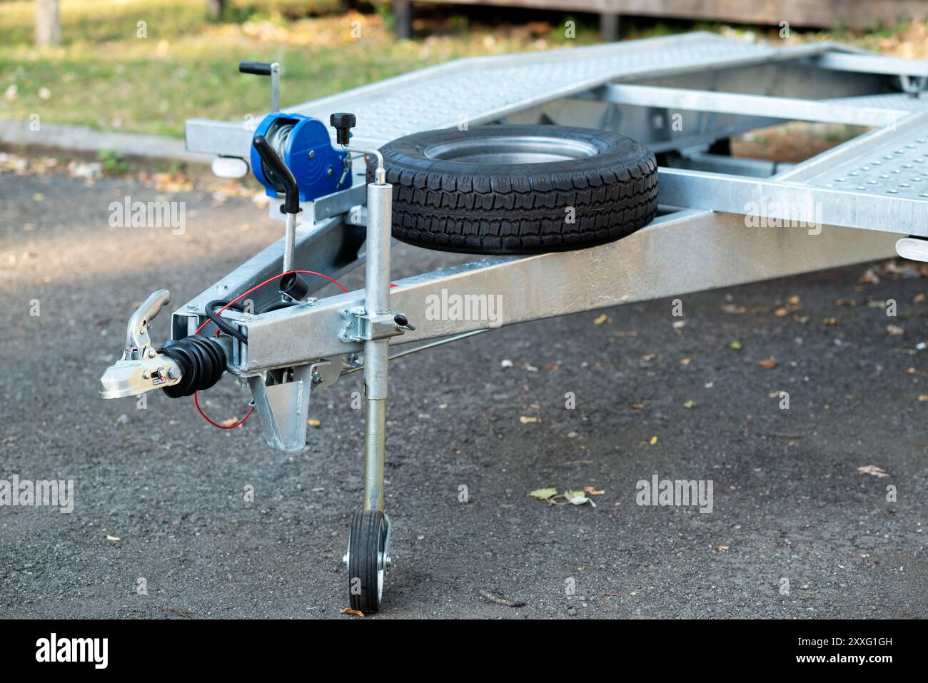 Primo piano di un attacco per rimorchio in metallo con una ruota di scorta montata e un verricello manuale. Foto Stock