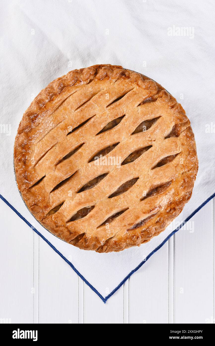 Vista dall'alto di una torta di mele appena sfornata su un asciugamano da cucina bianco, formato verticale. Foto Stock