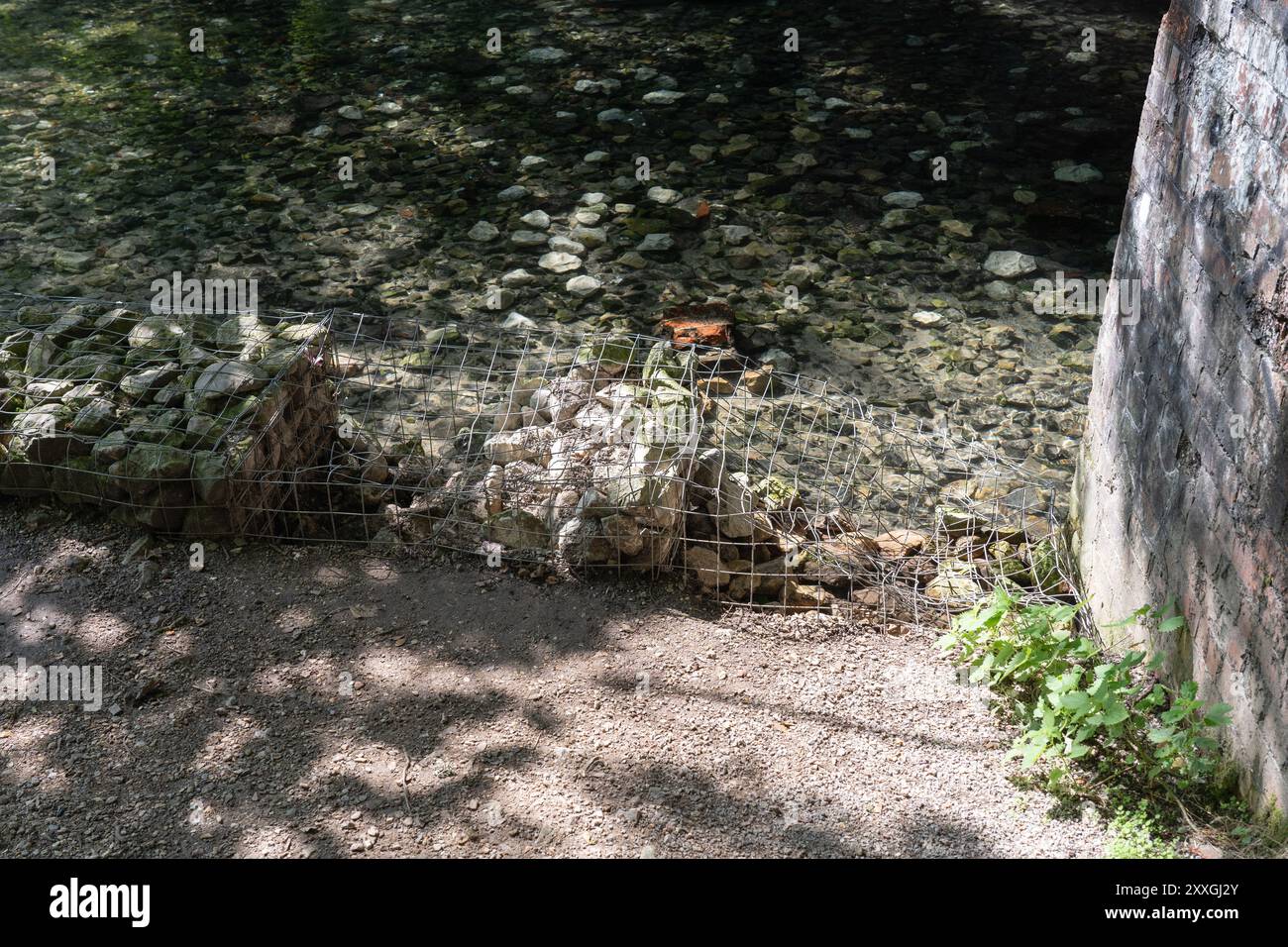 La protezione contro l'erosione del gabbione che protegge un sentiero è stata vandalizzata con fili tagliati e pietre mancanti. River Loddon, Old Basing, Basingstoke, Regno Unito Foto Stock