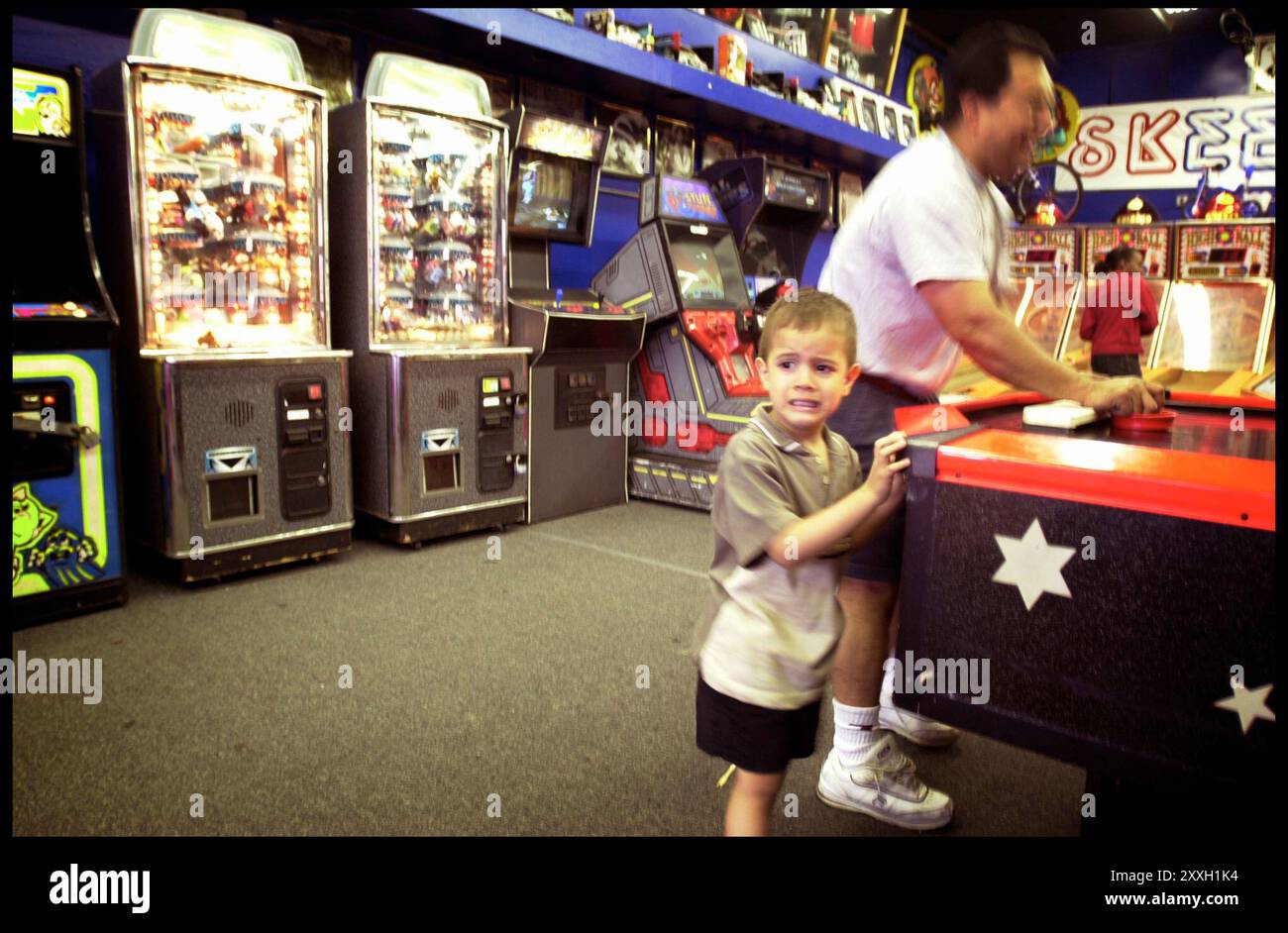 Parco divertimenti e passeggiata sul lungomare di Coney Island. Bambino infelice accanto a papà che gioca a hockey da tavolo. Foto Stock