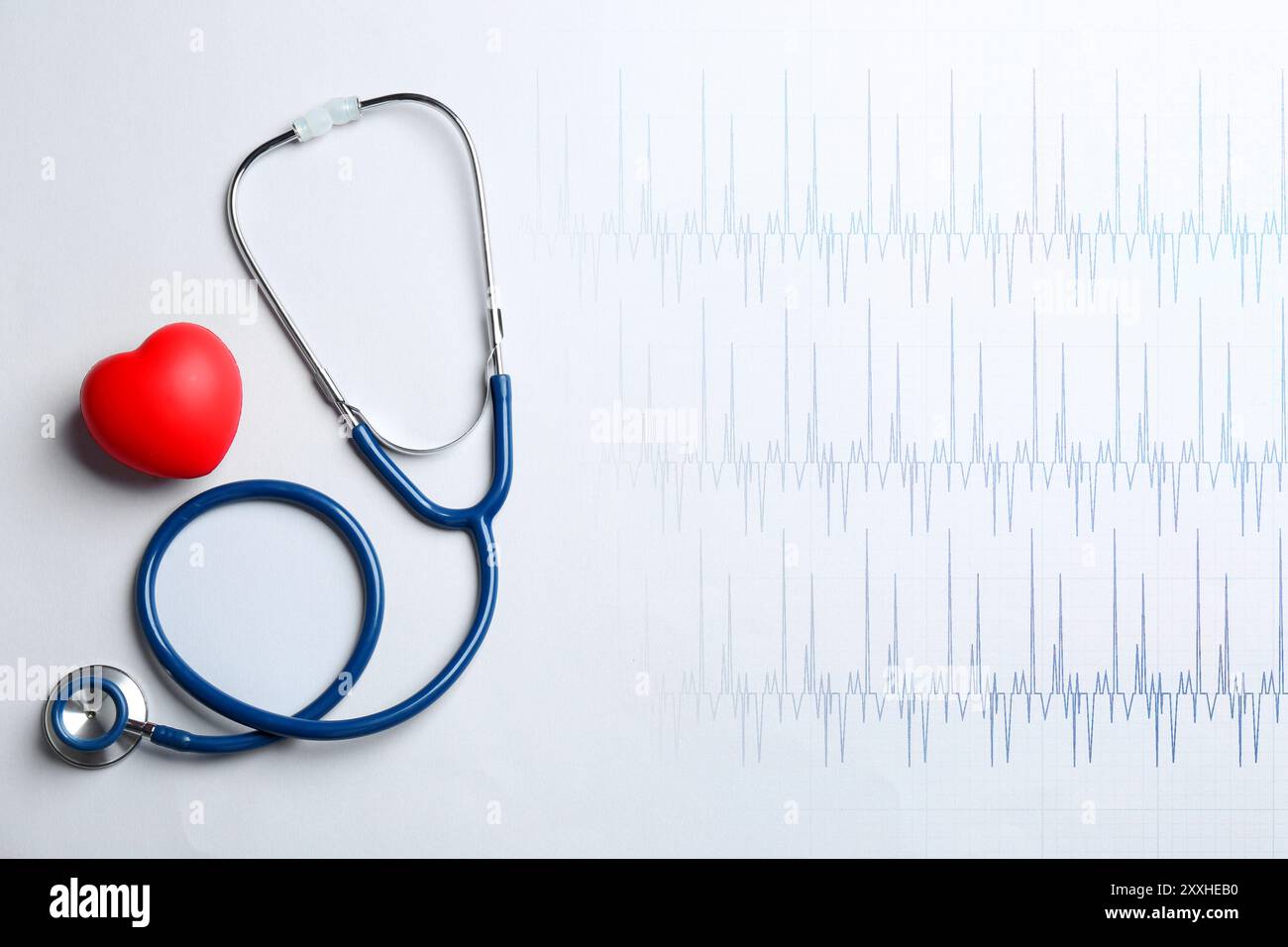 Cuore decorativo rosso, stetoscopio ed elettrocardiogramma su sfondo bianco, vista dall'alto Foto Stock