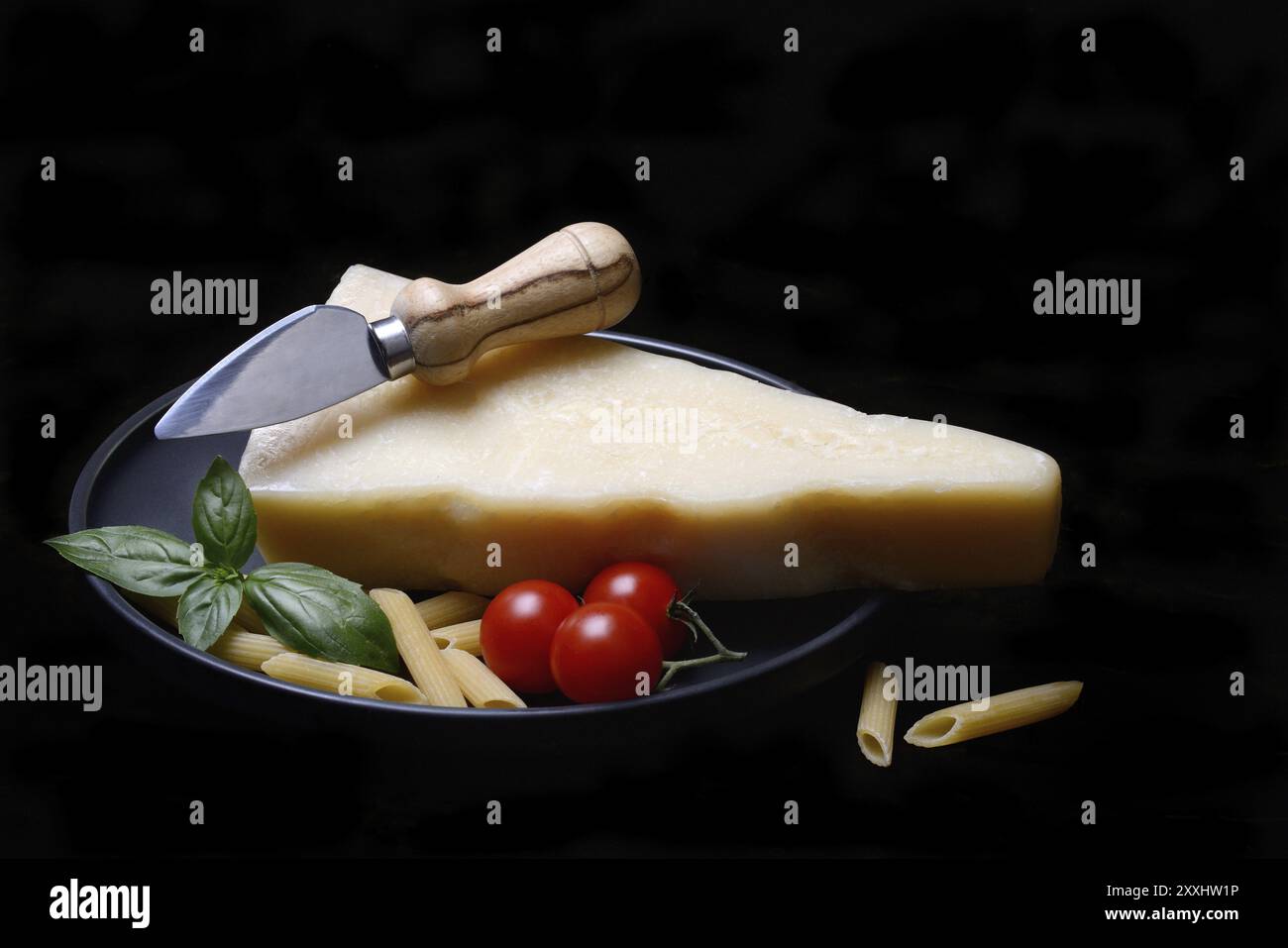 Un pezzo di parmigiano con coltello al formaggio, pasta e pomodori, Italia, Europa Foto Stock