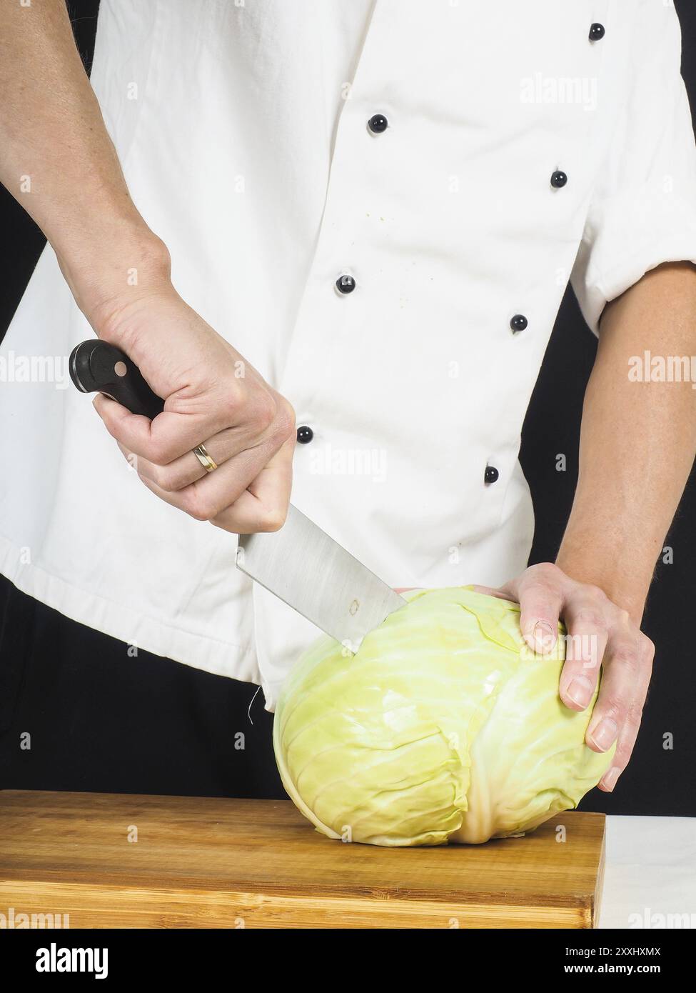 Chef professionale tenendo un affilato coltello da cucina su un cavolo cappuccio intero Foto Stock