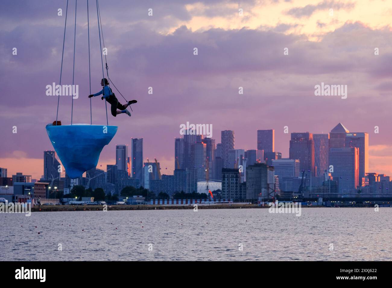 Londra, Regno Unito, 24 agosto 2024. La prima europea di "THAW" al Greenwich+Docklands International Festival (GDIF) ha visto la partecipazione di tre artisti aerei in cima a un blocco di ghiaccio che si scioglie da 2,5 tonnellate, sospeso sopra Gallions Point Marina, nel corso di 8 ore. Lo spettacolo, ripetuto ancora il 25 agosto, visibile dalla University of East London a Newham, è stato creato dalla compagnia teatrale australiana Legs on the Wall, dopo gli incendi boschivi del 2019/20 e sollecita l'umanità ad affrontare la crisi climatica. Credito: Fotografia dell'undicesima ora/Alamy Live News Foto Stock