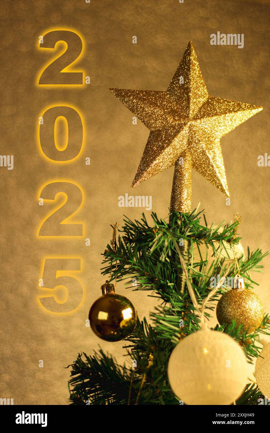 Foto ravvicinata di un albero di Natale con una stella in cima, decorata con sfere e luci gialle. Preparazione per l'idea di festeggiare il nuovo anno. 2025. Foto Stock