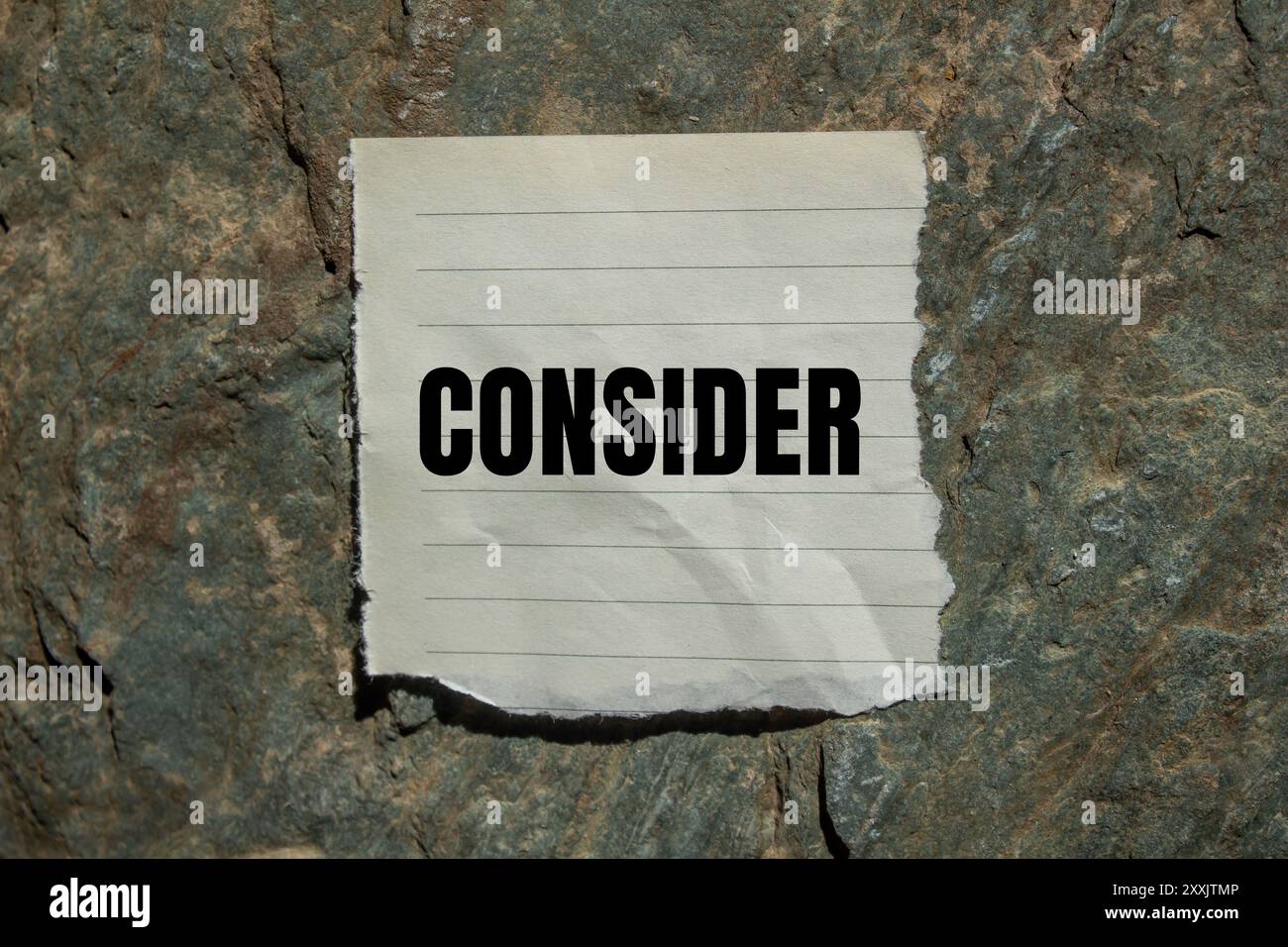 Considerare il messaggio scritto su un pezzo di carta strappato con sfondo in pietra. Simbolo concettuale da considerare. Copia spazio. Foto Stock