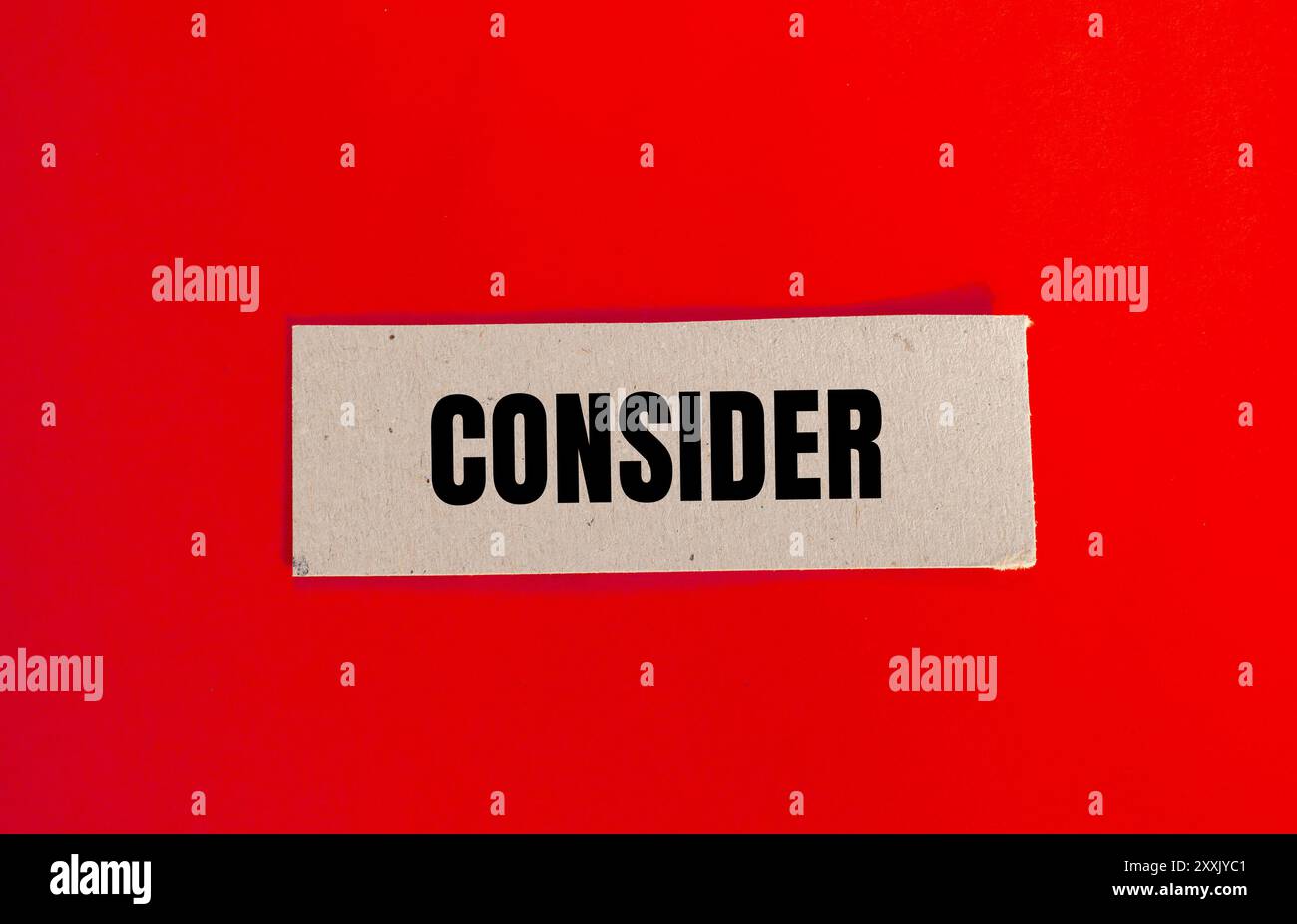 Considerare il messaggio scritto su un pezzo di carta con sfondo rosso. Simbolo concettuale da considerare. Copia spazio. Foto Stock