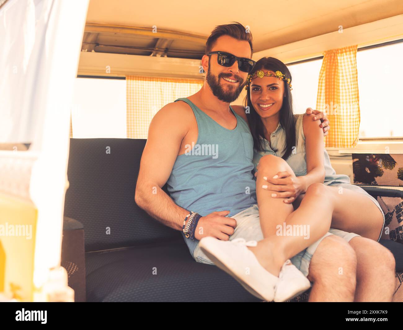 Amore hippie. Felice giovane coppia che si unisce e sorride mentre si siede sui sedili posteriori del minivan Foto Stock