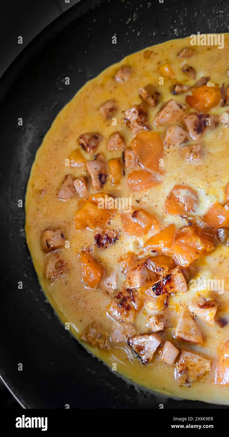Uova fritte con funghi e pomodori gialli in una padella. Cucina casalinga. Foto verticale Foto Stock
