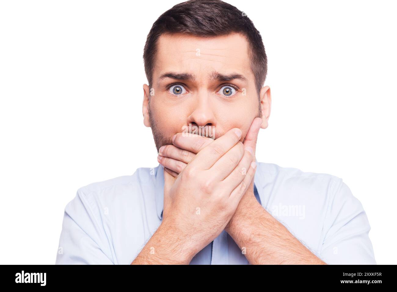 Assolutamente no! Un giovane scioccato in abbigliamento formale che copre la bocca con le mani e guarda la fotocamera mentre si trova su uno sfondo bianco Foto Stock Assolutamente no! Un giovane scioccato in abbigliamento formale che copre la bocca con le mani e guarda la fotocamera mentre si trova su uno sfondo bianco Foto Stock