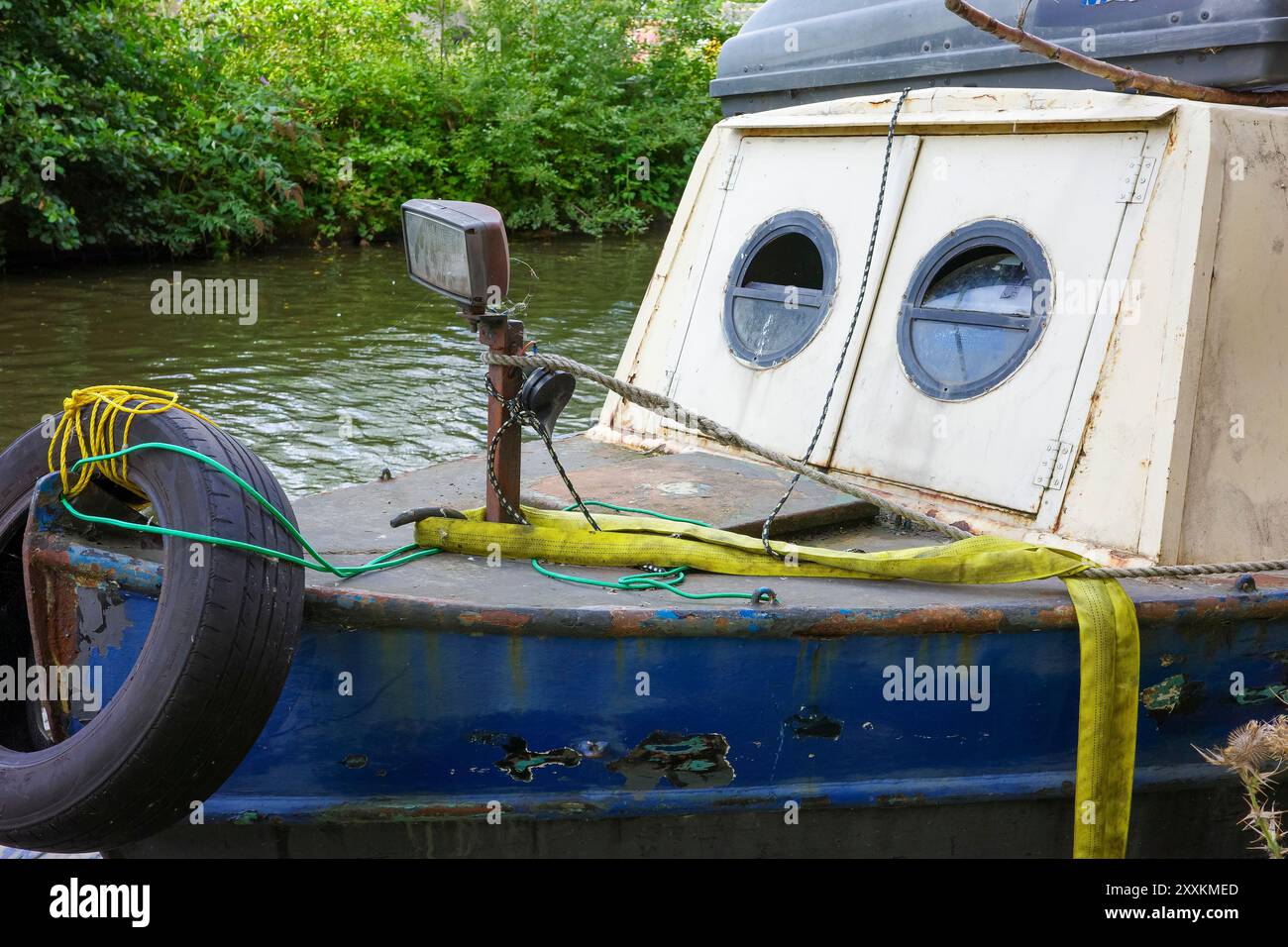 Manchester, Greater Manchester, Regno Unito. 24 agosto 2024: Una vecchia barca ancorata su un fiume sereno. L'esterno della barca mostra segni di ruggine e pai Foto Stock