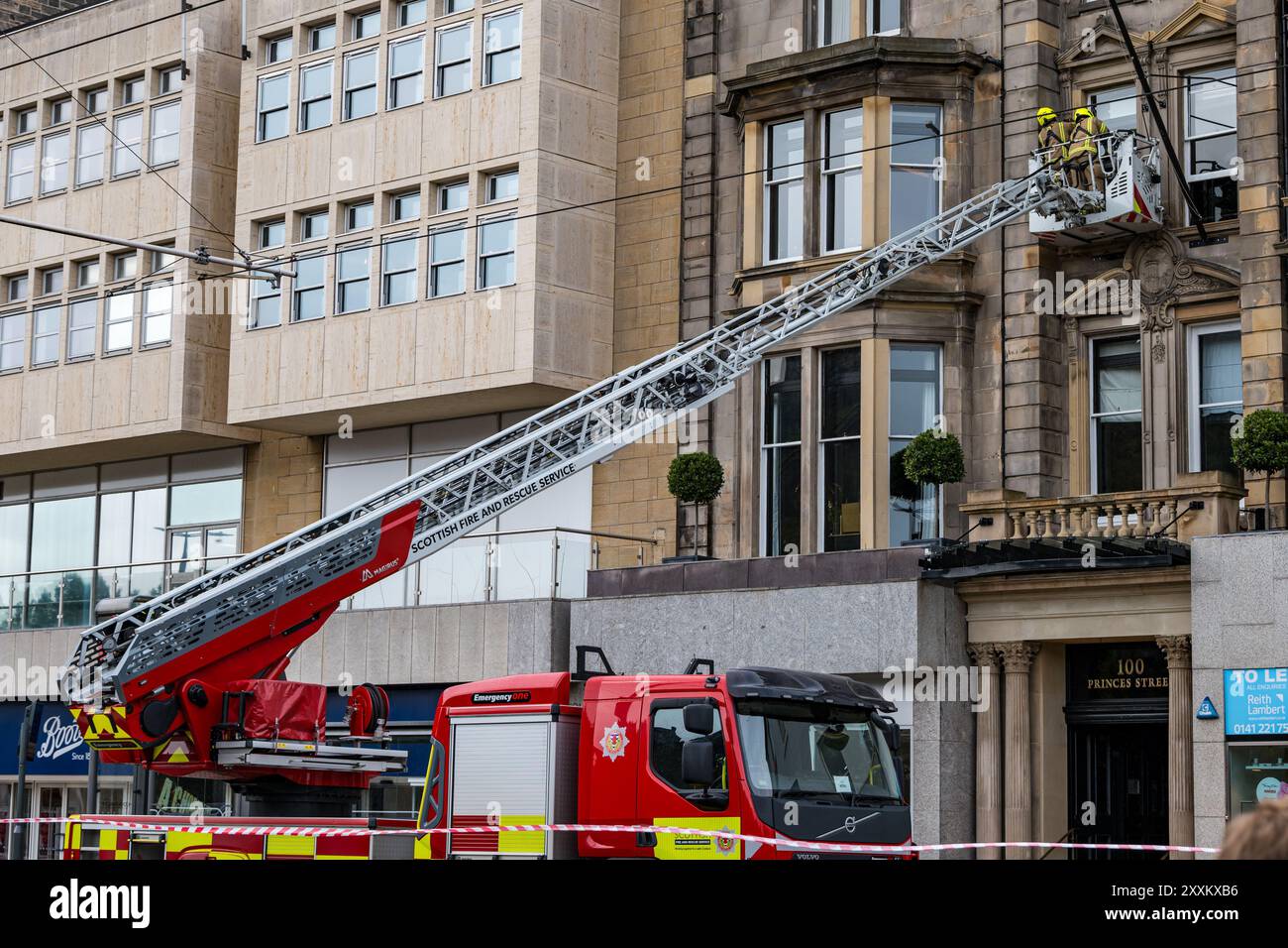 Princes Street, Edimburgo, Scozia, Regno Unito, 25 agosto 2024. I vigili del fuoco e la polizia assistono all'incidente: Due paletti al 100 Princes Street Hotel dovevano essere rimossi dai vigili del fuoco su una gru a causa di problemi di sicurezza nel vento forte con i motori antincendio che chiudevano la strada. Crediti: Sally Anderson/Alamy Live News Foto Stock