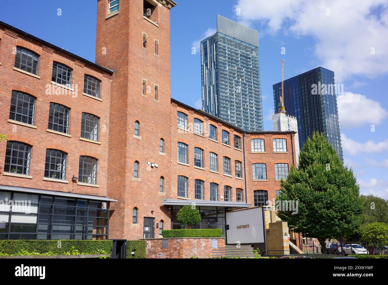 Manchester, Greater Manchester, Regno Unito. 24 agosto 2024: Edificio industriale ristrutturato con moderni grattacieli sullo sfondo in una giornata di sole. Foto Stock