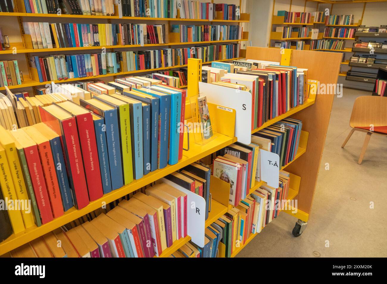 Libri su uno scaffale in biblioteca. Interno con molti libri vari sugli scaffali di una biblioteca pubblica. Copenaghen, Danimarca - 11 marzo 2024. Foto Stock