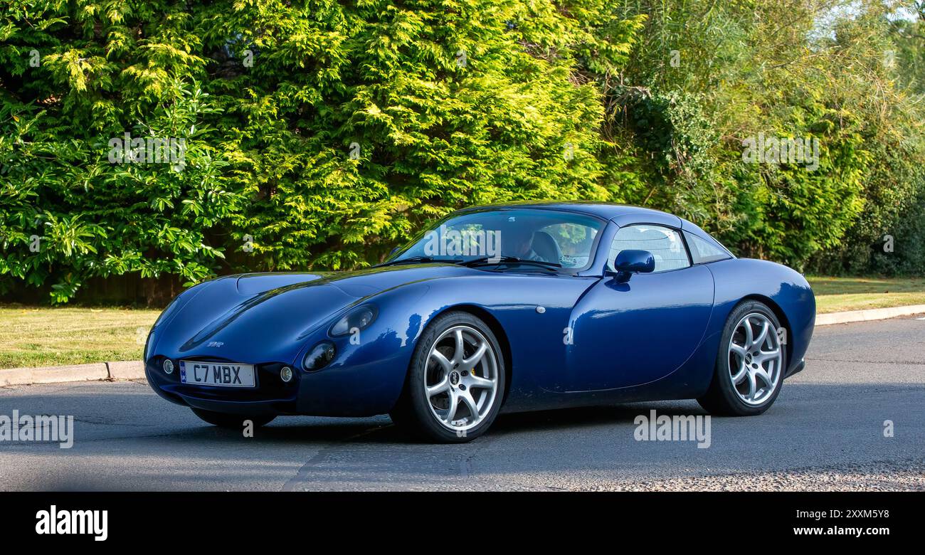 Whittlebury, Northants., Regno Unito - 25 agosto 2024: 2005 auto toscana blu TVR che guida su una strada di campagna britannica. Foto Stock