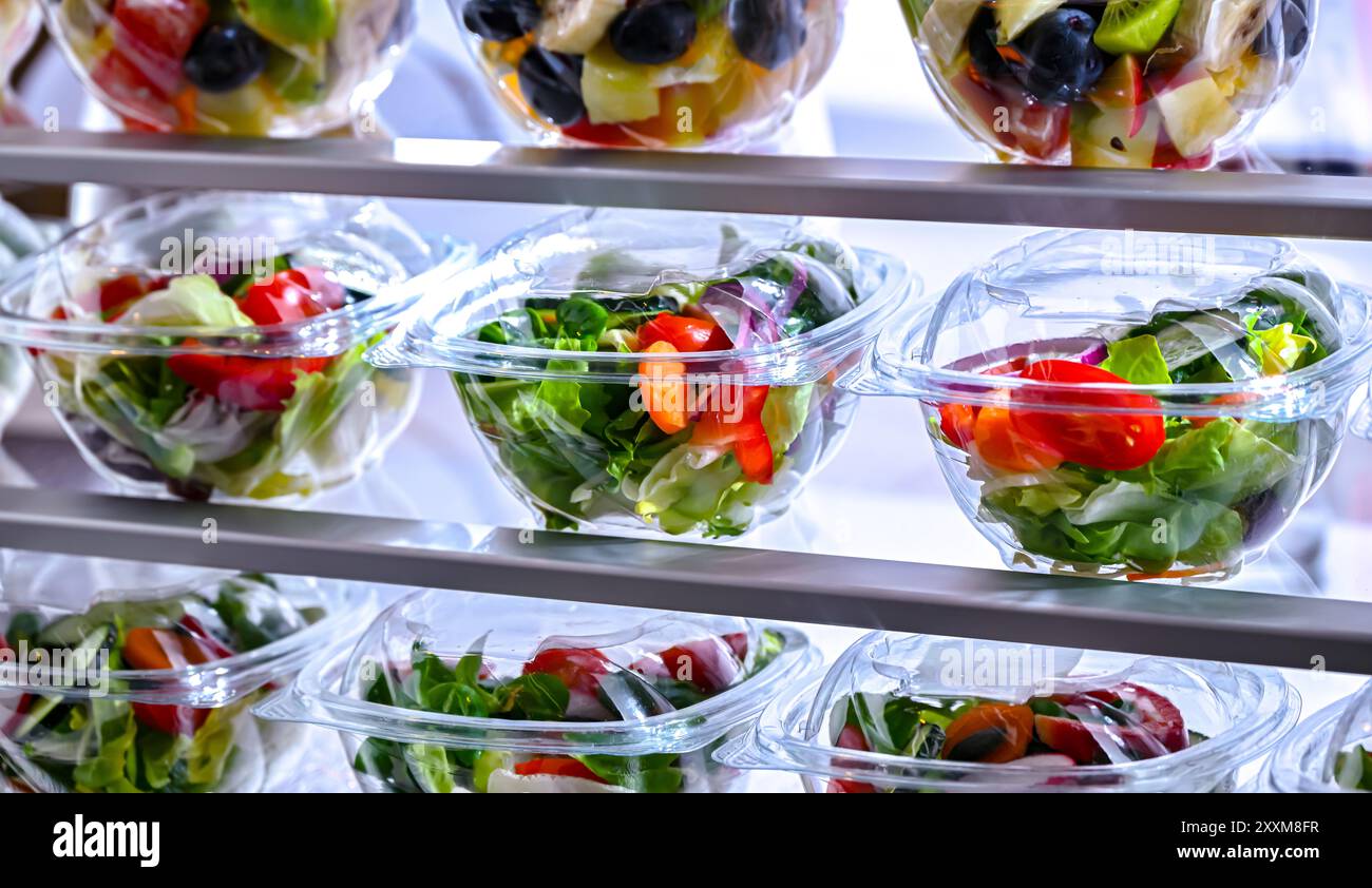 Scatole di plastica con insalate di frutta e verdura preconfezionate, messe in vendita in un frigorifero commerciale Foto Stock