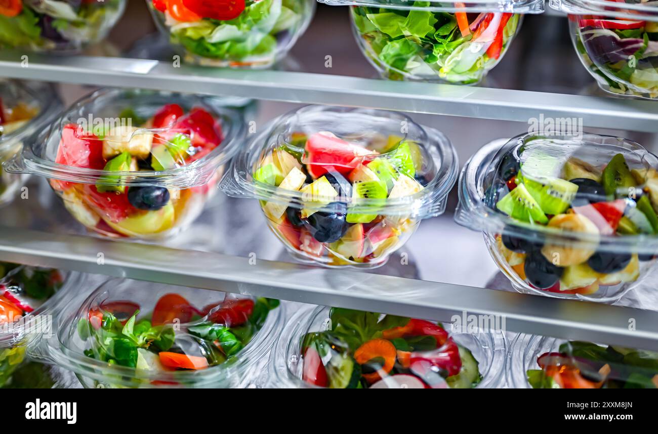 Scatole di plastica con insalate di frutta e verdura preconfezionate, messe in vendita in un frigorifero commerciale Foto Stock