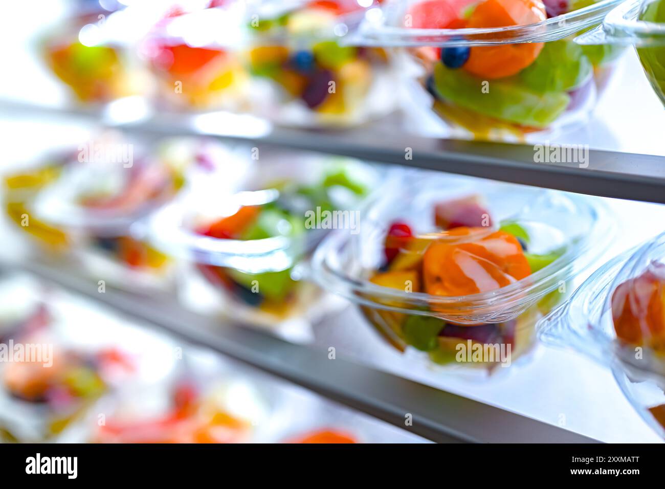 Scatole di plastica con macedonie di frutta preconfezionate, messe in vendita in un frigorifero commerciale Foto Stock