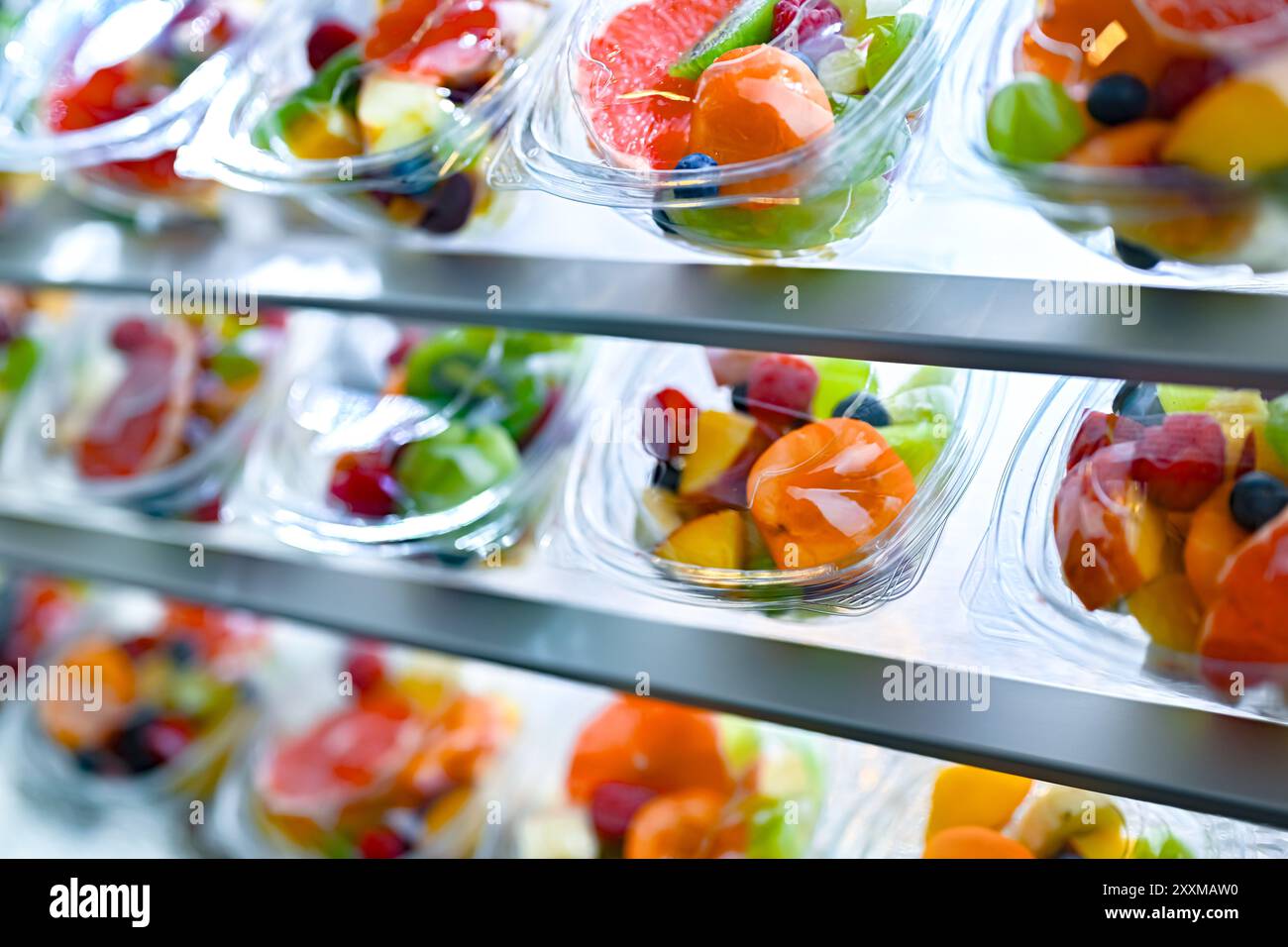 Scatole di plastica con macedonie di frutta preconfezionate, messe in vendita in un frigorifero commerciale Foto Stock