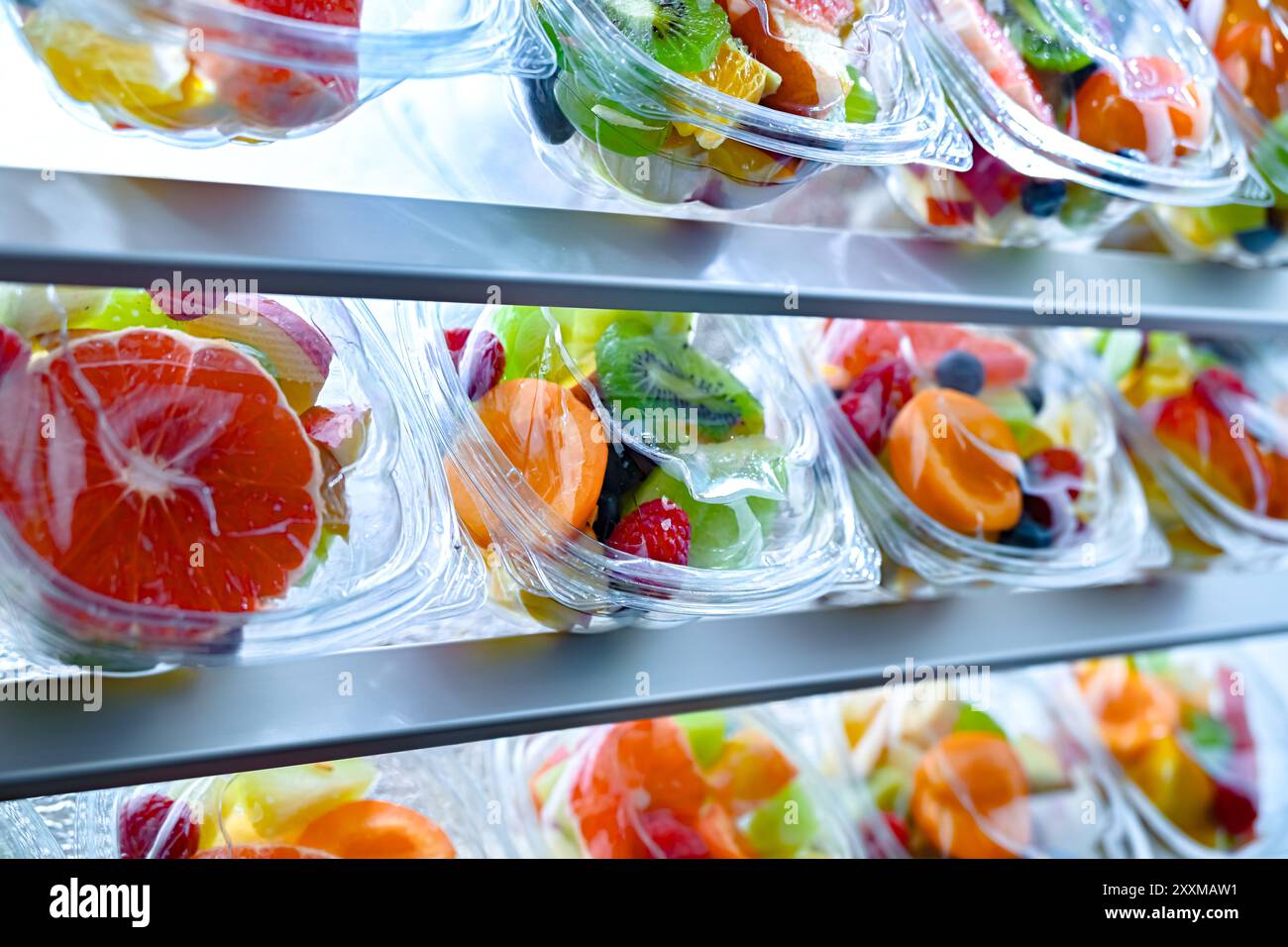 Scatole di plastica con macedonie di frutta preconfezionate, messe in vendita in un frigorifero commerciale Foto Stock