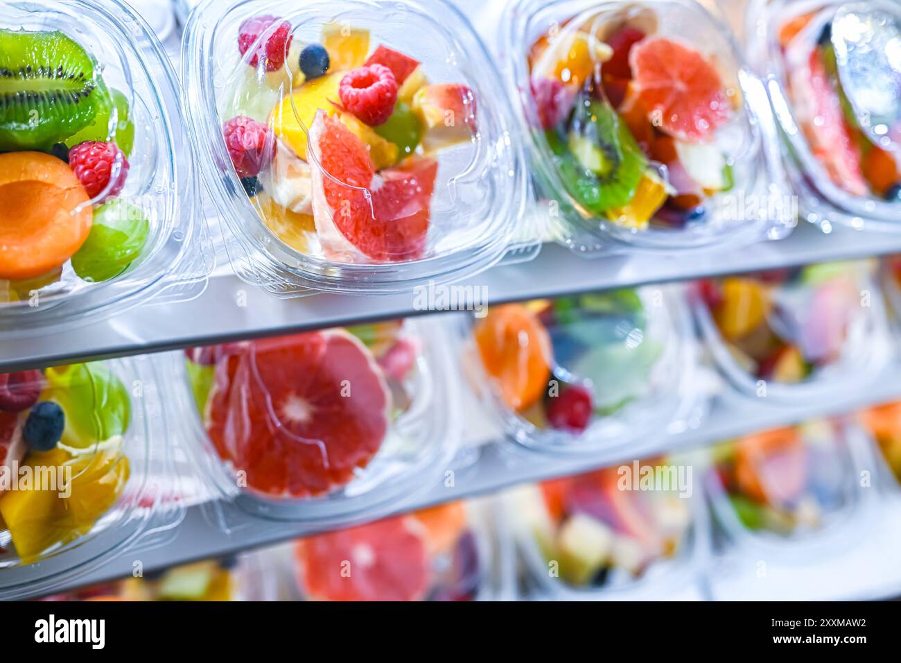 Scatole di plastica con macedonie di frutta preconfezionate, messe in vendita in un frigorifero commerciale Foto Stock