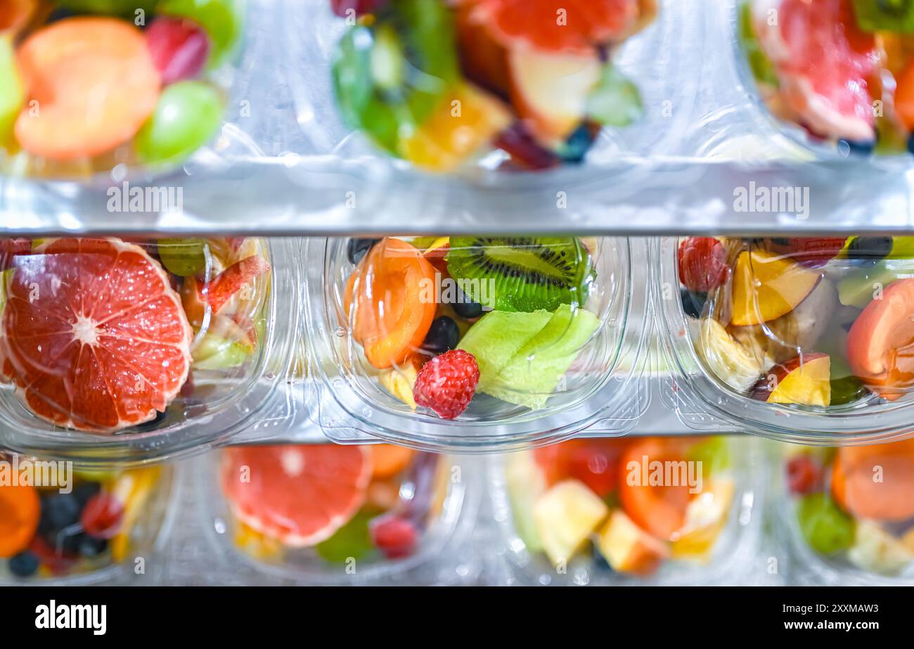 Scatole di plastica con macedonie di frutta preconfezionate, messe in vendita in un frigorifero commerciale Foto Stock