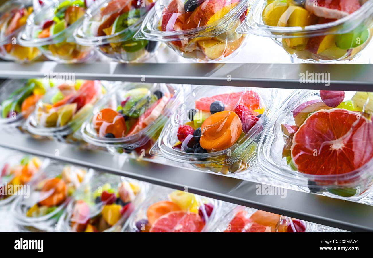 Scatole di plastica con macedonie di frutta preconfezionate, messe in vendita in un frigorifero commerciale Foto Stock