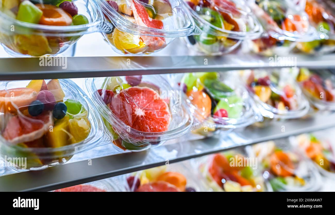 Scatole di plastica con macedonie di frutta preconfezionate, messe in vendita in un frigorifero commerciale Foto Stock