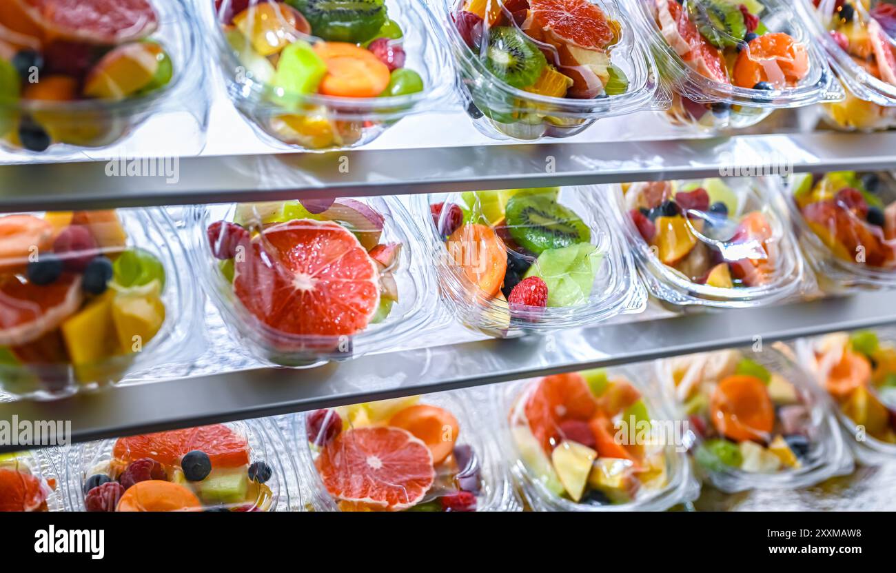 Scatole di plastica con macedonie di frutta preconfezionate, messe in vendita in un frigorifero commerciale Foto Stock
