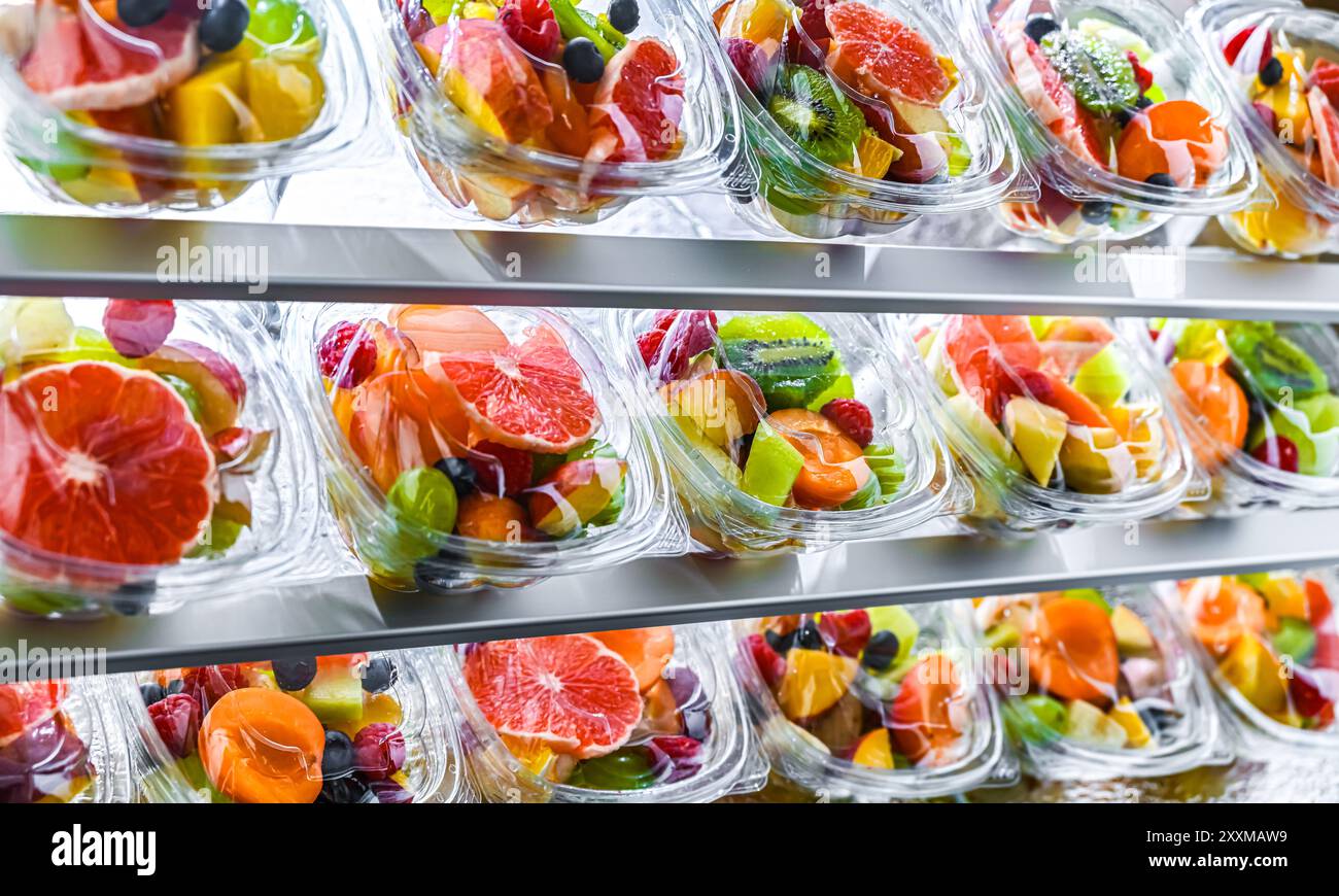 Scatole di plastica con macedonie di frutta preconfezionate, messe in vendita in un frigorifero commerciale Foto Stock