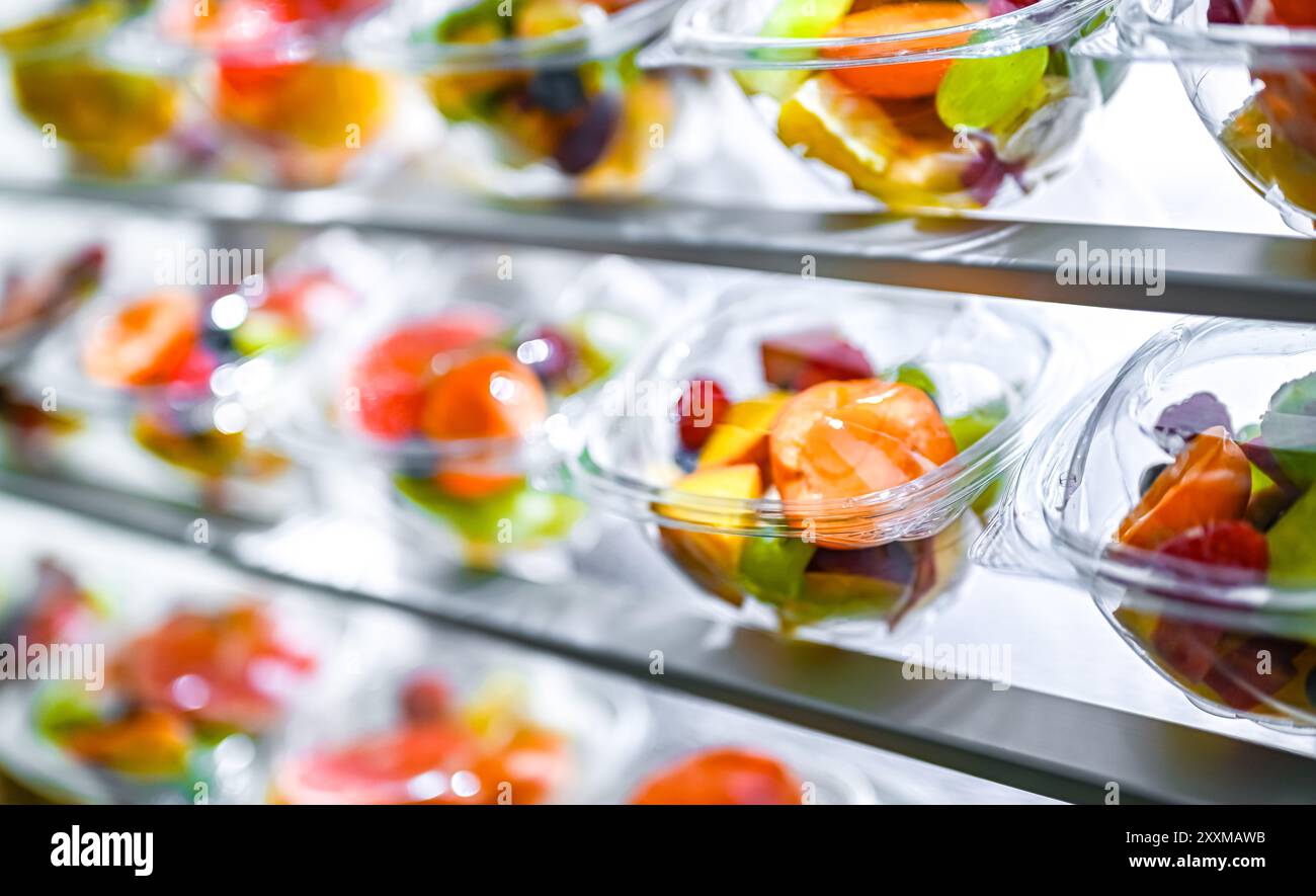 Scatole di plastica con macedonie di frutta preconfezionate, messe in vendita in un frigorifero commerciale Foto Stock
