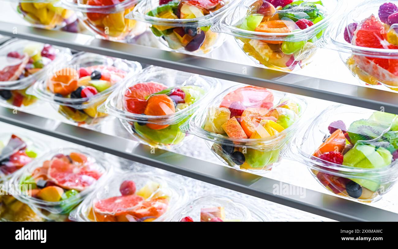 Scatole di plastica con macedonie di frutta preconfezionate, messe in vendita in un frigorifero commerciale Foto Stock