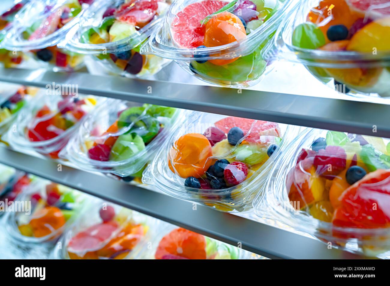Scatole di plastica con macedonie di frutta preconfezionate, messe in vendita in un frigorifero commerciale Foto Stock
