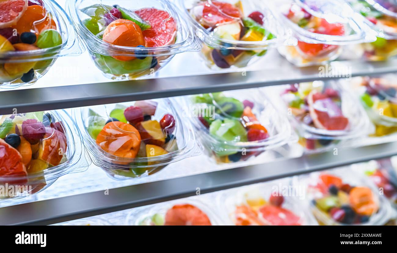 Scatole di plastica con macedonie di frutta preconfezionate, messe in vendita in un frigorifero commerciale Foto Stock