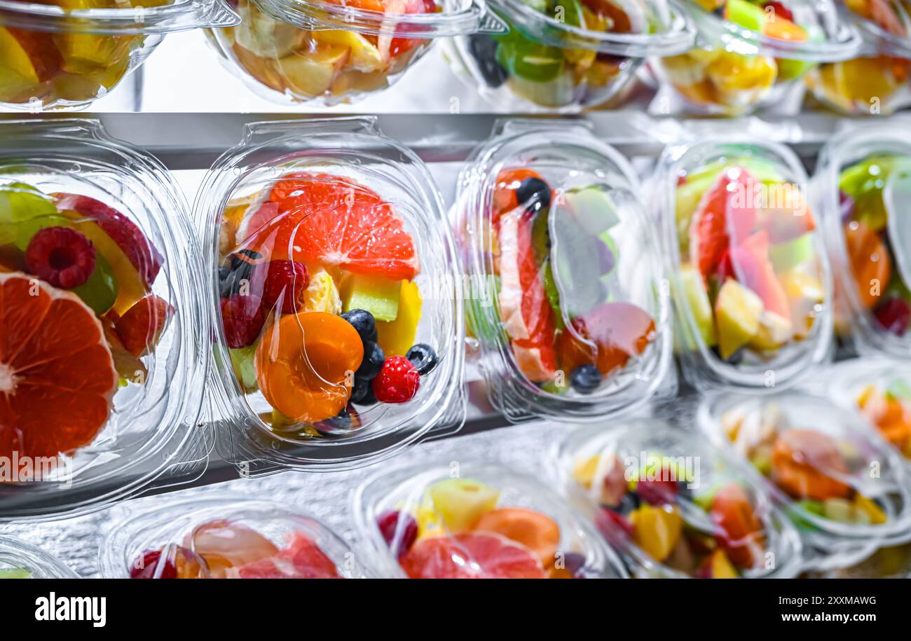 Scatole di plastica con macedonie di frutta preconfezionate, messe in vendita in un frigorifero commerciale Foto Stock