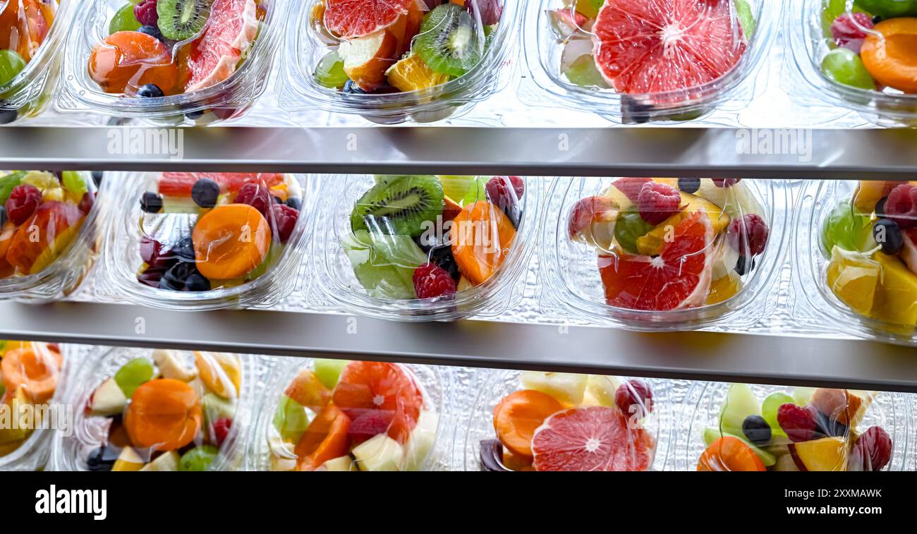 Scatole di plastica con macedonie di frutta preconfezionate, messe in vendita in un frigorifero commerciale Foto Stock