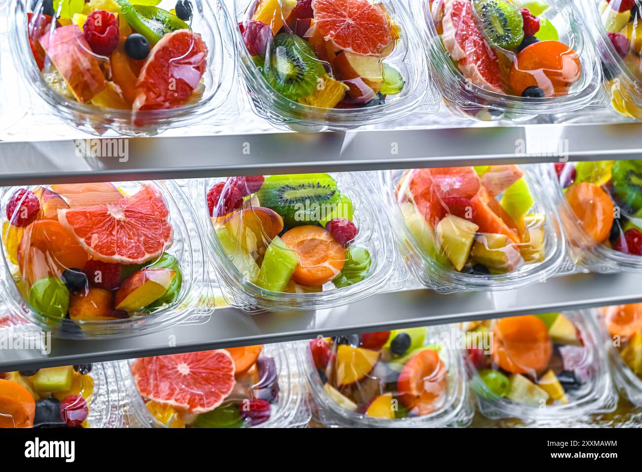 Scatole di plastica con macedonie di frutta preconfezionate, messe in vendita in un frigorifero commerciale Foto Stock