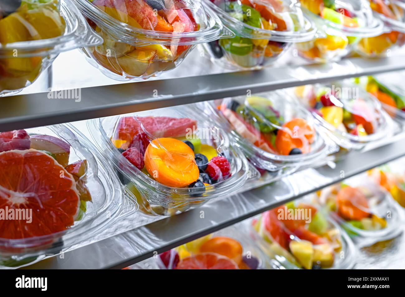 Scatole di plastica con macedonie di frutta preconfezionate, messe in vendita in un frigorifero commerciale Foto Stock