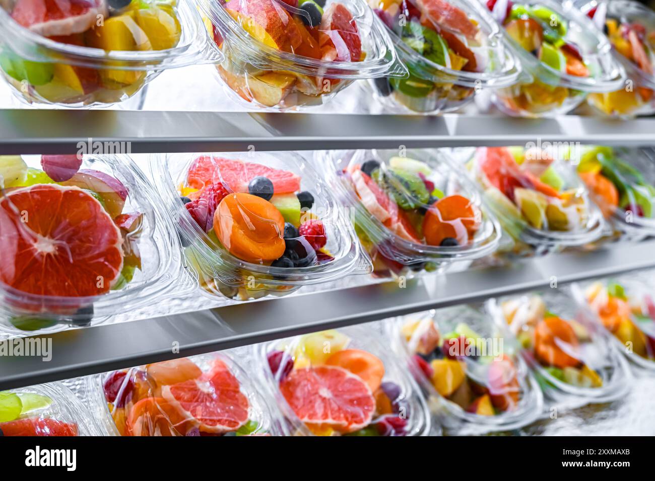 Scatole di plastica con macedonie di frutta preconfezionate, messe in vendita in un frigorifero commerciale Foto Stock