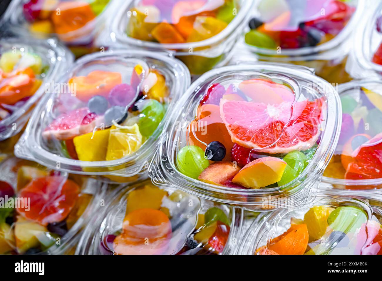 Scatole di plastica con macedonie di frutta preconfezionate, messe in vendita in un frigorifero commerciale Foto Stock