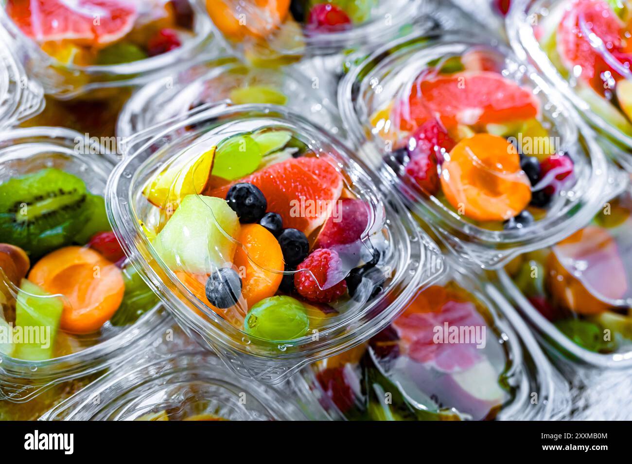 Scatole di plastica con macedonie di frutta preconfezionate, messe in vendita in un frigorifero commerciale Foto Stock