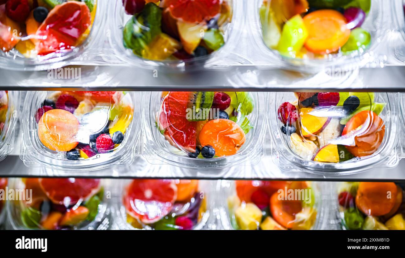 Scatole di plastica con macedonie di frutta preconfezionate, messe in vendita in un frigorifero commerciale Foto Stock